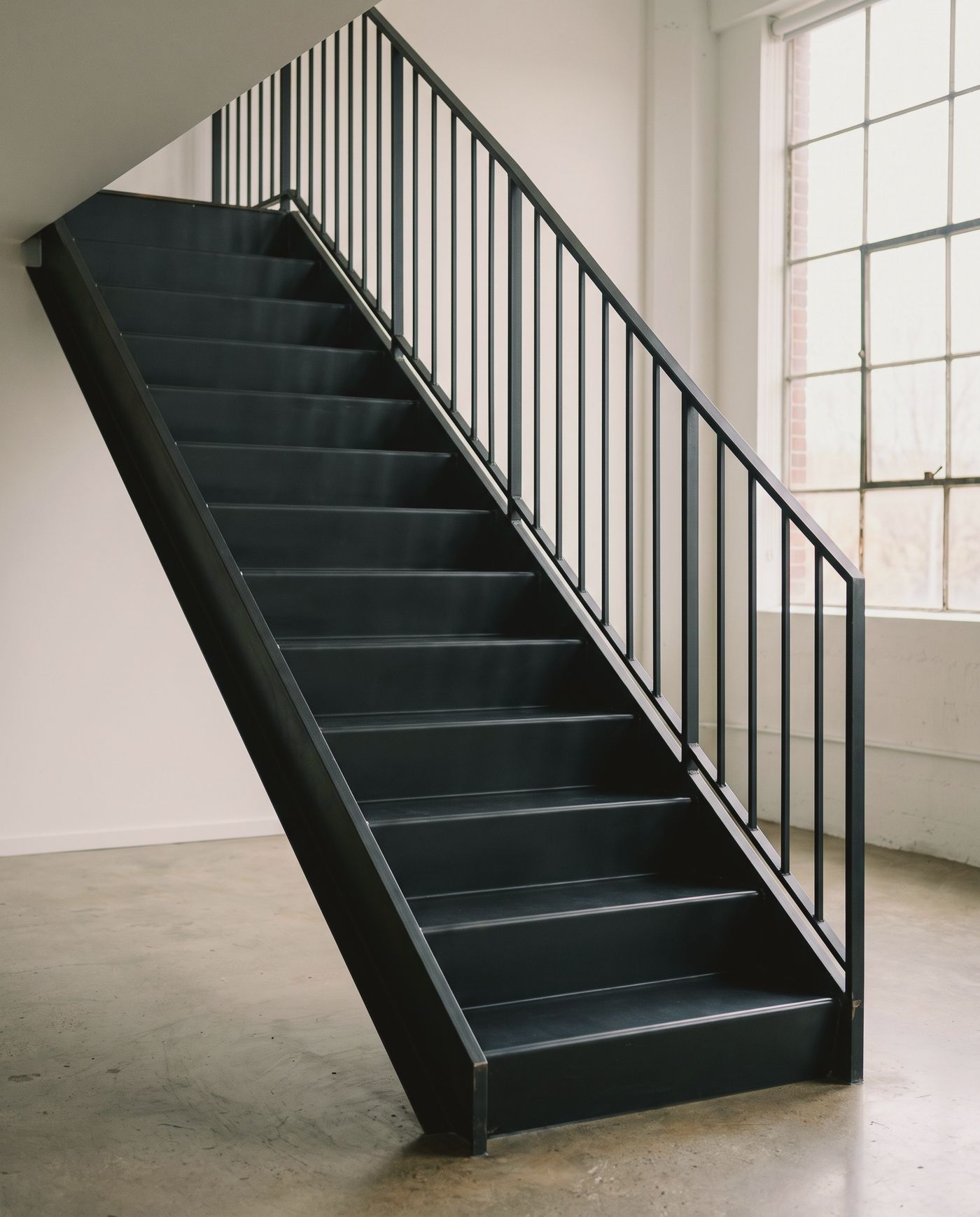 Image créée par IA : escalier droit à limons en acier et marches en tôle pliée vers une mezzanine